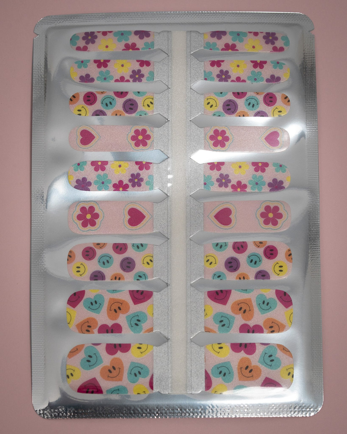 SHEESH Nails – Big Smile, Bild 06: Kinder-Nagelfolie Big Smile mit farbenfrohen Blumen-, Herz- und Smiley-Designs in geöffneter Folienverpackung.