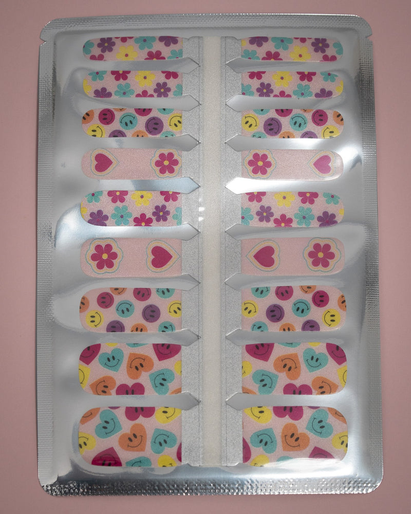 SHEESH Nails – Big Smile, Bild 06: Kinder-Nagelfolie Big Smile mit farbenfrohen Blumen-, Herz- und Smiley-Designs in geöffneter Folienverpackung.
