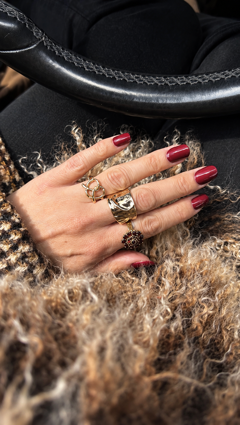 SHEESH Nails – Bordeauxrote Cat Eye Maniküre mit goldenen Ringen am Lenkrad.