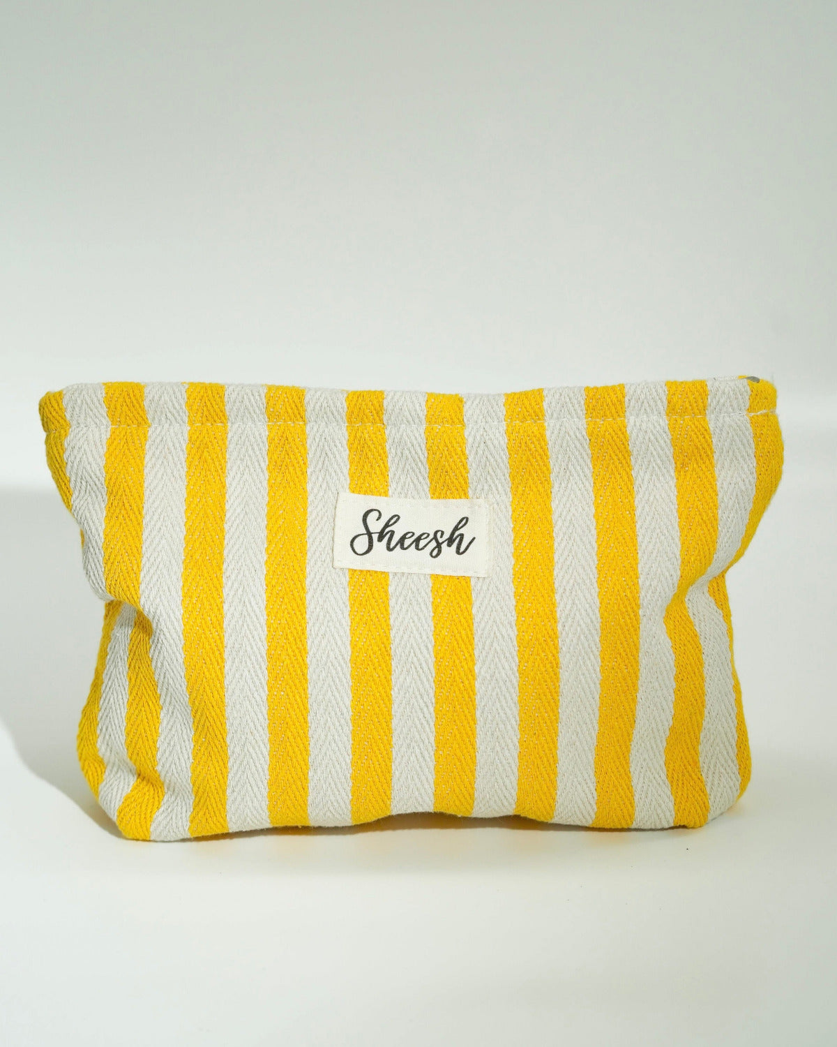 Produktfoto der Sheesh Beauty Bag in Gelb und Weiß. Die gestreifte Kosmetiktasche besteht aus robustem Stoff und trägt das Sheesh-Logo auf der Vorderseite. Ideal zur Aufbewahrung von Nagelfolien, Tools oder Beauty-Produkten – praktisch, stilvoll und wiederverwendbar.