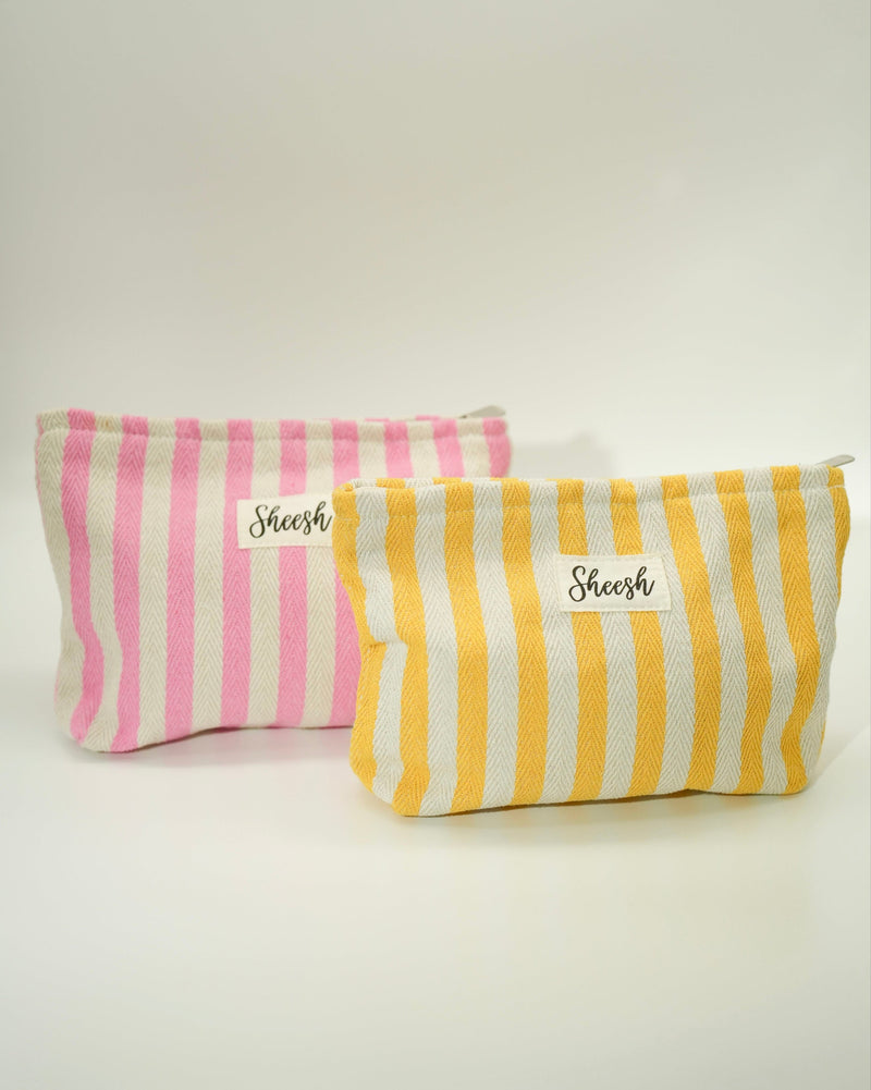 Produktfoto zweier Sheesh Beauty Bags in Rosa-Weiß und Gelb-Weiß. Die gestreiften Kosmetiktaschen bestehen aus robustem Stoff und tragen das Sheesh-Logo auf der Vorderseite. Ideal zur Aufbewahrung von Nagelfolien, Tools oder Beauty-Produkten – stilvoll, praktisch und wiederverwendbar.