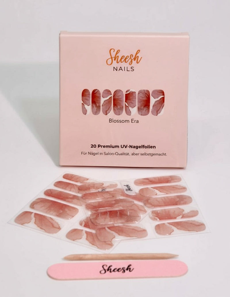 Produktaufnahme der Sheesh Nails UV-Nagelfolie „Blossom Era“. Die Folien zeigen ein zartes, roséfarbenes Design mit dezentem Glanz, das für einen eleganten und femininen Look sorgt. Die hochwertige Verpackung und das beigelegte Zubehör betonen den professionellen Anspruch – ideal für romantische Styles und moderne Nail-Looks.
