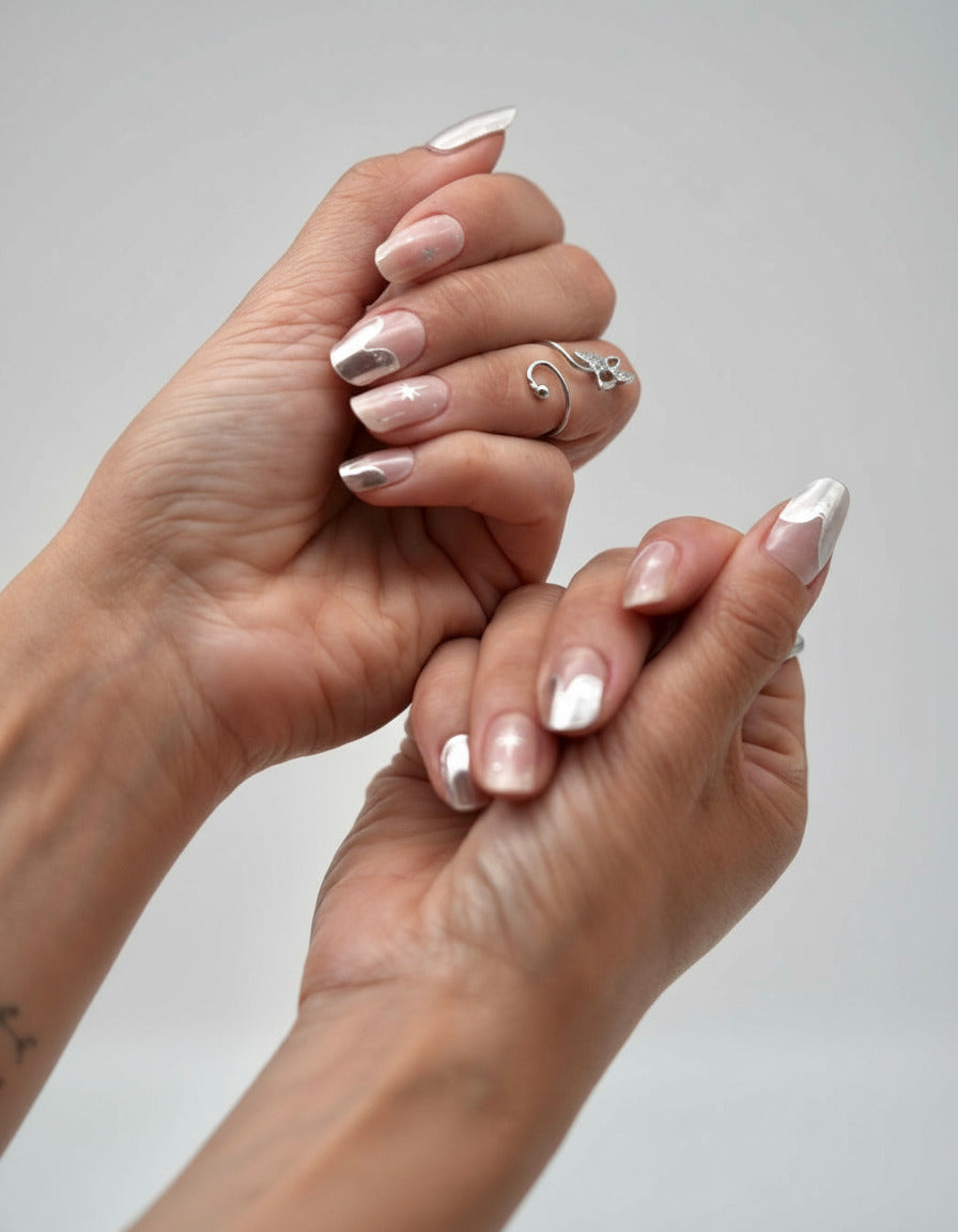 Nahaufnahme einer Hand mit den Sheesh Nails UV-Nagelfolien „Cosmic Crunch“. Die Folien zeigen ein elegantes Nude mit metallisch-silbernem Schimmer und dezentem Chrom-Glanz, der das Licht wunderschön reflektiert. Der Look wirkt edel, modern und zugleich futuristisch – perfekt für besondere Anlässe, Abendlooks oder einen stilvollen Alltagsauftritt mit kosmischem Flair.