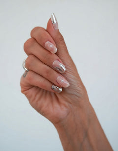 Nahaufnahme einer Hand mit den Sheesh Nails UV-Nagelfolien „Cosmic Crunch“. Die Folien zeigen ein elegantes Nude mit metallisch-silbernem Schimmer und dezentem Chrom-Glanz, der das Licht wunderschön reflektiert. Der Look wirkt edel, modern und zugleich futuristisch – perfekt für besondere Anlässe, Abendlooks oder einen stilvollen Alltagsauftritt mit kosmischem Flair.