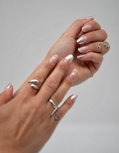 Nahaufnahme einer Hand mit den Sheesh Nails UV-Nagelfolien „Cosmic Crunch“. Die Folien zeigen ein elegantes Nude mit metallisch-silbernem Schimmer und dezentem Chrom-Glanz, der das Licht wunderschön reflektiert. Der Look wirkt edel, modern und zugleich futuristisch – perfekt für besondere Anlässe, Abendlooks oder einen stilvollen Alltagsauftritt mit kosmischem Flair.