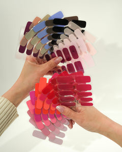 Produktfoto eines Folienfächers mit verschiedenen Sheesh Nails UV-Nagelfolien in zahlreichen Farben. Die Hand hält den aufgefächerten Überblick von Rot-, Rosa-, Lila- und Blautönen. Ideal zur Farbauswahl und Präsentation des Sortiments – professionell, übersichtlich und ästhetisch arrangiert.