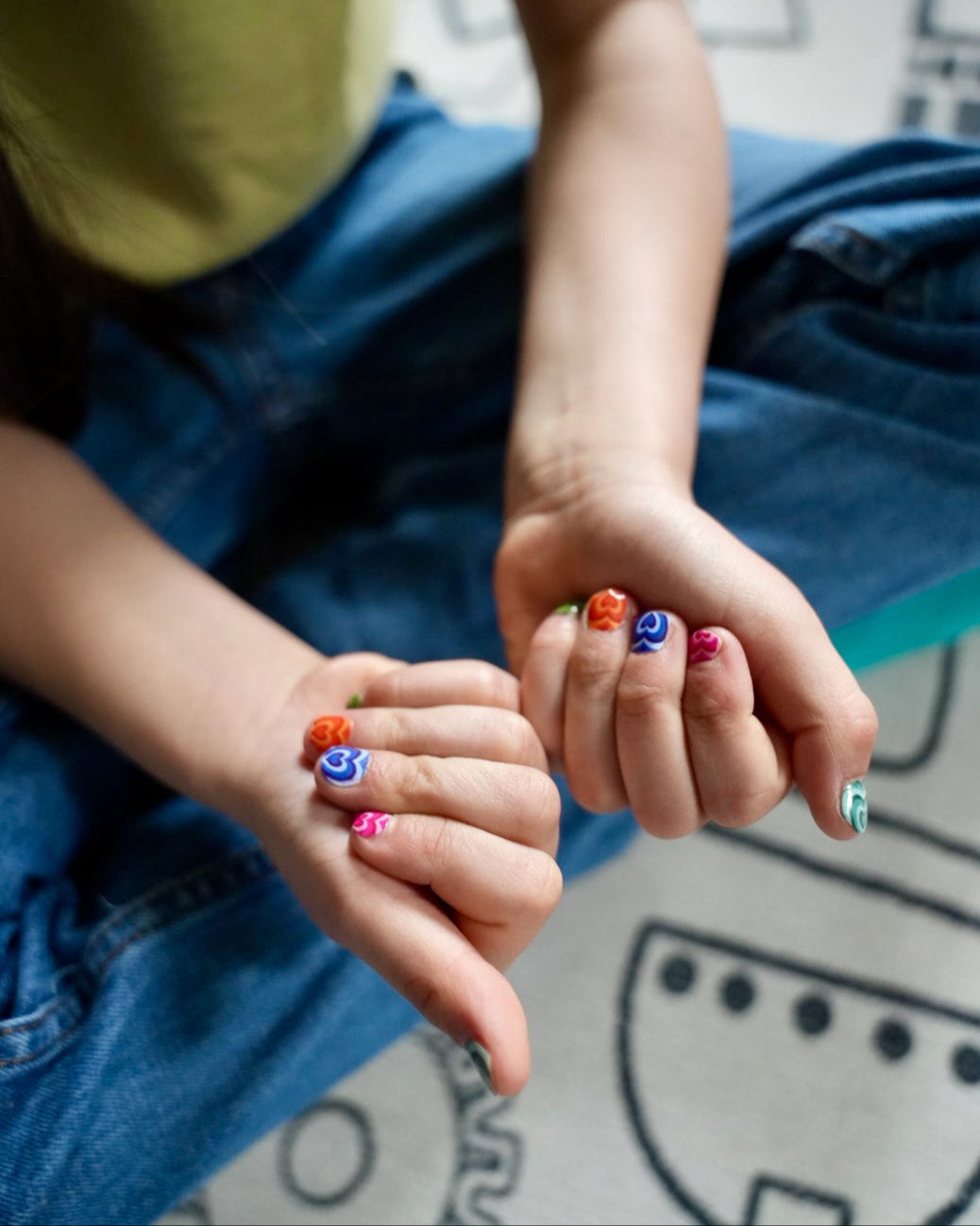 Nahaufnahme eines Kindes mit Sheesh Nails Kinder-Nagelfolien „Herzi“. Die selbstklebenden Sticker zeigen bunte Herzmotive auf farbenfrohem Hintergrund. Das Design wirkt verspielt und kindgerecht. Die Folien sind hautfreundlich, ungiftig und leicht anzubringen – ideal für kreative Kinder-Maniküren mit Liebe zum Detail.