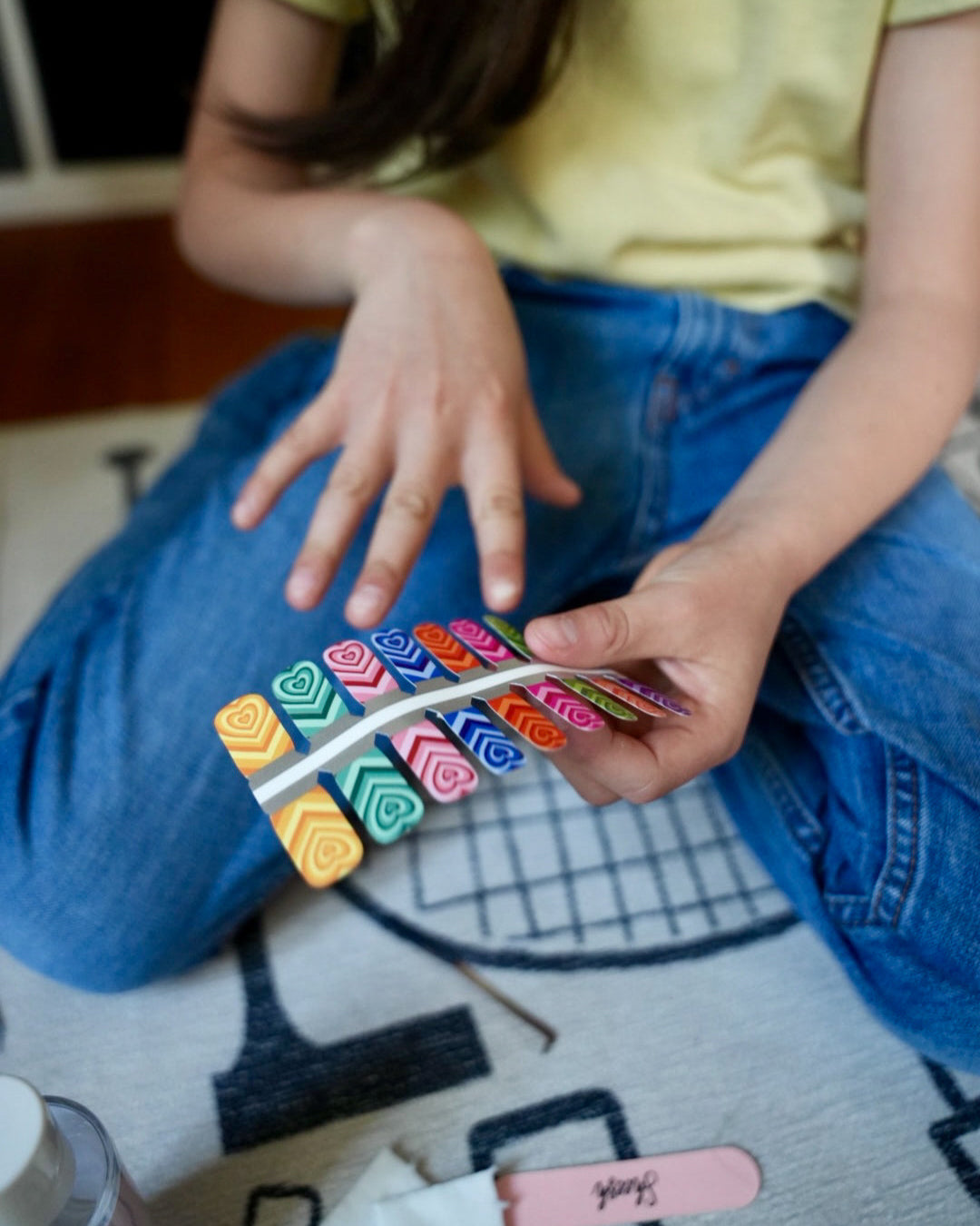 Nahaufnahme eines Kindes mit Sheesh Nails Kinder-Nagelfolien „Herzi“. Die selbstklebenden Sticker zeigen bunte Herzmotive auf farbenfrohem Hintergrund. Das Design wirkt verspielt und kindgerecht. Die Folien sind hautfreundlich, ungiftig und leicht anzubringen – ideal für kreative Kinder-Maniküren mit Liebe zum Detail.