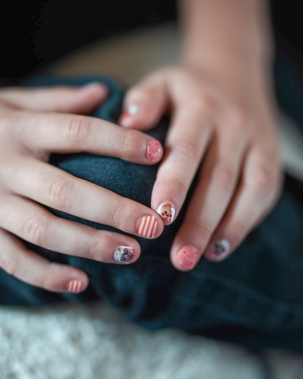 Nahaufnahme einer Kinderhand, die Sheesh Nails Kinder-Nagelfolien „Hot Dog“ aufträgt. Die selbstklebenden Sticker zeigen ein fröhliches Design in Orange mit Streifen und kleinen Hundemotiven. Das deckende Finish sorgt für einen lebendigen, kindgerechten Look. Hautfreundlich, ungiftig und leicht anzubringen – ideal für kreative Kinder-Maniküren mit Spaß und Farbe.