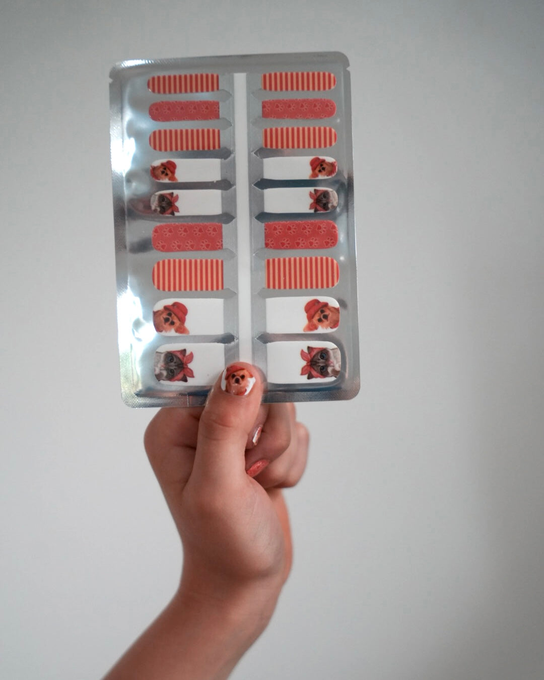 Nahaufnahme einer Kinderhand mit den Sheesh Nails Kinder-Nagelfolien „Hot Dog“. Die selbstklebenden Sticker zeigen ein verspieltes Design in Orange mit Streifen und kleinen Hundemotiven. Das deckende Finish sorgt für einen farbenfrohen, kindgerechten Look. Hautfreundlich, ungiftig und einfach anzubringen – ideal für kreative Kinder-Maniküren mit Spaß und Fantasie.