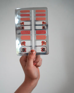 Nahaufnahme einer Kinderhand mit den Sheesh Nails Kinder-Nagelfolien „Hot Dog“. Die selbstklebenden Sticker zeigen ein verspieltes Design in Orange mit Streifen und kleinen Hundemotiven. Das deckende Finish sorgt für einen farbenfrohen, kindgerechten Look. Hautfreundlich, ungiftig und einfach anzubringen – ideal für kreative Kinder-Maniküren mit Spaß und Fantasie.