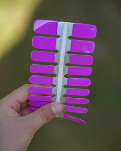 Nahaufnahme einer Kinderhand mit den Sheesh Nails Kinder-Nagelfolien „Lila Laune“. Die selbstklebenden Sticker leuchten in kräftigem Violett und bringen gute Stimmung auf kleine Nägel. Das vollflächig deckende Design sorgt für einen fröhlichen, modernen Look, der Spaß und Kreativität ausdrückt. Die Sticker sind leicht anzubringen, hautfreundlich, ungiftig und lassen sich rückstandsfrei wieder entfernen – ganz ohne UV-Lampe. Perfekt für kreative kleine Nail-Artists, die Farbe und Freude lieben.