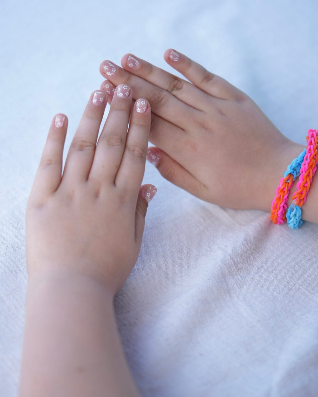 Nahaufnahme einer Kinderhand mit den Sheesh Nails Kinder-Nagelfolien „Lilly“. Die transparenten Sticker zeigen feine, weiße Blumen und lassen die natürliche Nagelfarbe sanft durchscheinen. Ideal für kleine Nail-Artists, die verspielte, zarte Designs lieben. Die selbstklebenden Folien sind leicht anzubringen, hautfreundlich, ungiftig und lassen sich rückstandsfrei wieder entfernen – ganz ohne UV-Lampe. Perfekt für kreative Kinder-Maniküren mit einem natürlichen und liebevollen Look.