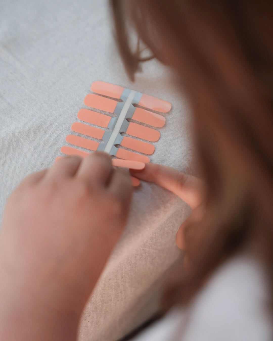Nahaufnahme einer Kinderhand mit den Sheesh Nails Kinder-Nagelfolien „Peach“. Die zarten Pfirsichfarben verleihen kleinen Nägeln einen weichen, natürlichen Look. Die selbstklebenden, deckenden Sticker lassen sich leicht aufkleben und rückstandsfrei wieder entfernen – ganz ohne UV-Lampe. Das Design wirkt warm, freundlich und sorgt für eine gepflegte Kinder-Maniküre mit sanftem Glanz. Hautfreundlich, ungiftig und perfekt für kreative kleine Nail-Artists.