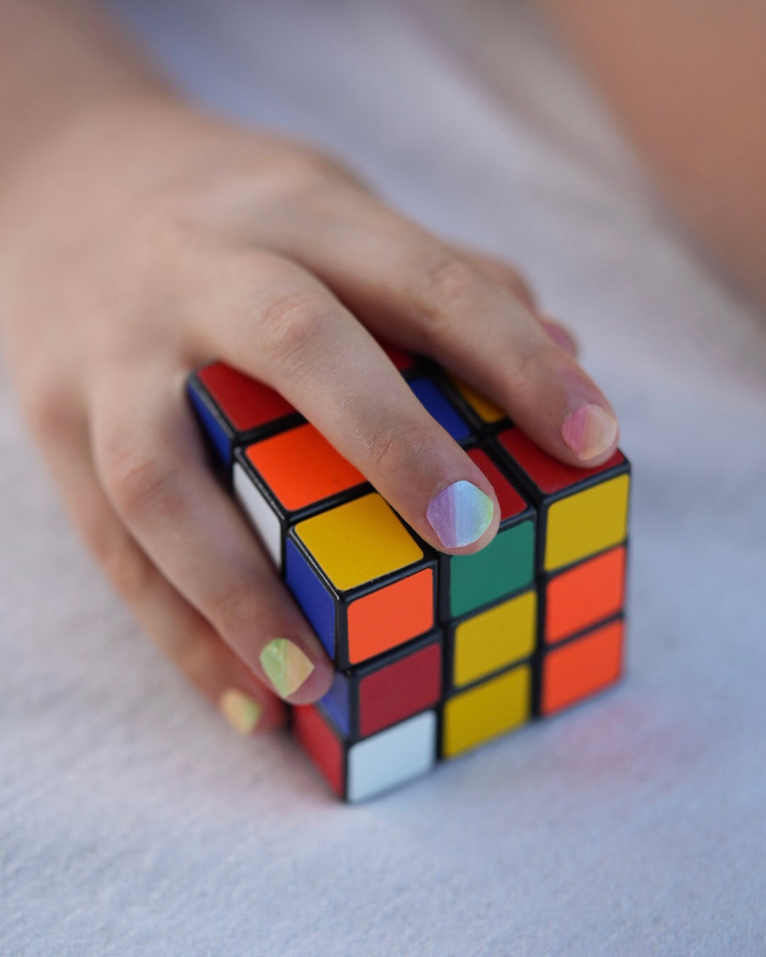 Nahaufnahme einer Kinderhand mit Sheesh Nails Kinder-Nagelfolien „Rainbow“. Die selbstklebenden Sticker zeigen ein fröhliches Regenbogendesign in sanften Pastelltönen. Das deckende Finish sorgt für einen gleichmäßigen, farbintensiven Look. Die Folien sind leicht anzubringen, hautfreundlich, ungiftig und lassen sich rückstandsfrei wieder entfernen – ideal für kreative Kinder-Maniküren mit Farbe und Spaß.