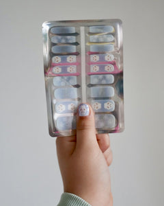 Kinderhand hältt blaue Schneemann Nagelfolien von SHEESH vor weißem Hintergrund  - winterliches Nageldesign für Kinder mit Schneemann-Motiv. 