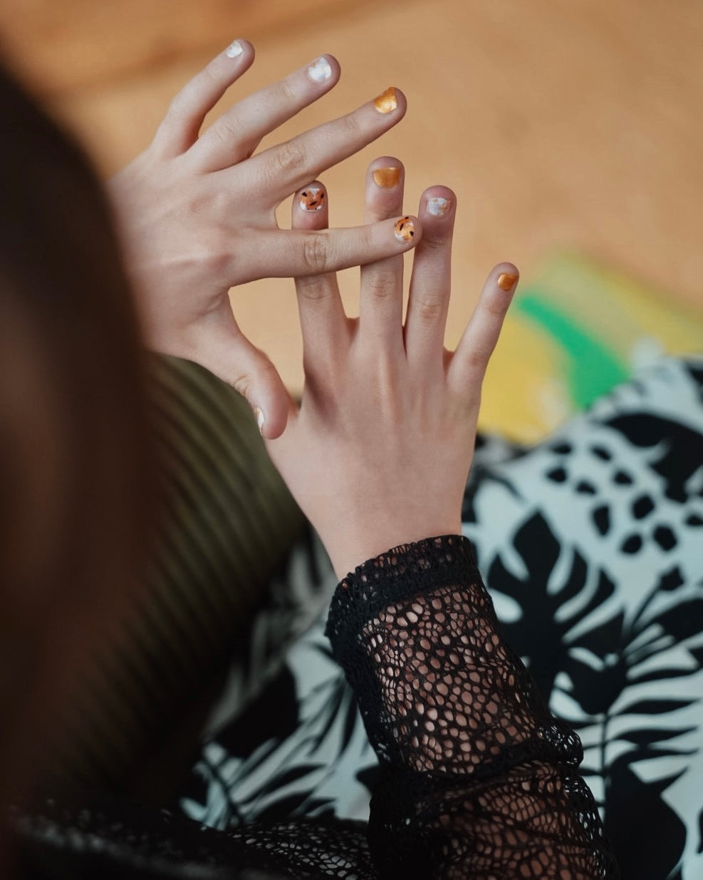 Nahaufnahme einer Kinderhand mit Sheesh Nails Kinder-Nagelfolien „Sonnenblume“. Die selbstklebenden Sticker zeigen ein fröhliches Design mit orangefarbenen und weißen Streifen sowie kleinen Sonnenblumenmotiven. Das verspielte Muster sorgt für einen sommerlichen, kindgerechten Look. Die Folien sind hautfreundlich, ungiftig und leicht anzubringen – ideal für kreative Kinder-Maniküren mit Blumenmotiven.