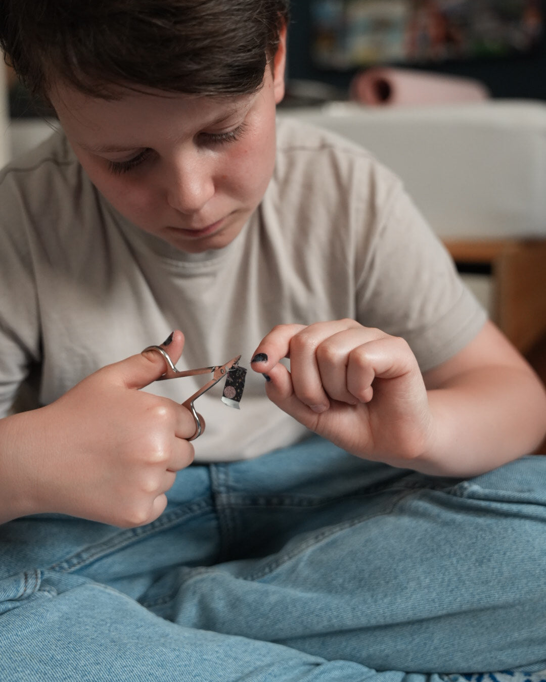Nahaufnahme einer Kinderhand mit den Sheesh Nails Kinder-Nagelfolien „Space“. Die selbstklebenden Sticker zeigen ein galaktisches Design mit bunten Planeten und Sternen auf schwarzem Hintergrund. Das deckende Finish sorgt für einen kräftigen, farbenfrohen Look. Hautfreundlich, ungiftig und einfach anzubringen – ideal für kreative Kinder-Maniküren mit Weltraum-Motiven.