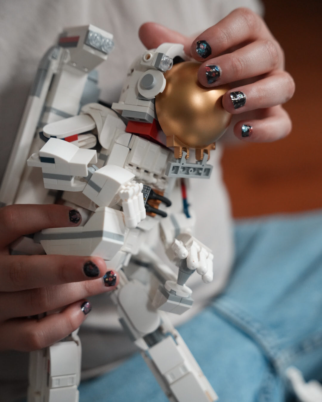 Nahaufnahme einer Kinderhand mit den Sheesh Nails Kinder-Nagelfolien „Space“. Die selbstklebenden Sticker zeigen ein galaktisches Design mit bunten Planeten und Sternen auf schwarzem Hintergrund. Das deckende Finish sorgt für einen kräftigen, farbenfrohen Look. Hautfreundlich, ungiftig und einfach anzubringen – ideal für kreative Kinder-Maniküren mit Weltraum-Motiven.