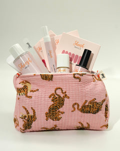Produktfoto des Sheesh Nails Limited Wild Starter Sets. Eine rosa Kosmetiktasche mit Tigerprint ist gefüllt mit Sheesh Nails Produkten wie UV-Lampe, Nail Care Pen, Cleaner und Nagelfolien. Das Set kombiniert Funktionalität mit stilvollem Design – ideal als Geschenk oder Einstieg in die Nagelfolienwelt.