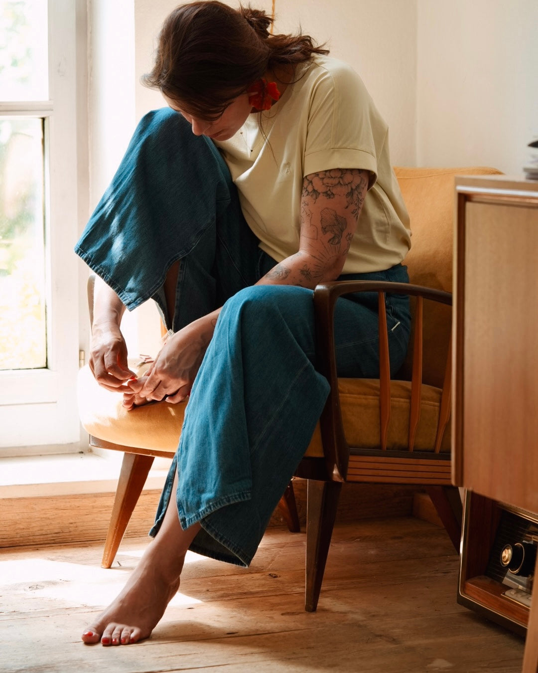 Frau bringt die Sheesh Nails Pedi UV-Nagelfolie „Lifeguard“ auf ihren Zehennägeln an. Die intensiv rote Folie sorgt für ein glänzendes, professionelles Finish wie im Salon. Das Bild zeigt den Anwendungsmoment in natürlichem Licht und vermittelt Pflege, Präzision und stilvolle Sommerästhetik.