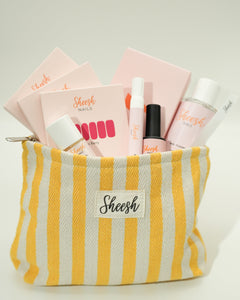Produktfoto des Sheesh Nails Starter Sets mit Beauty Bag. Das Set enthält UV-Lampe, Top Coat, Nail Cleanser, Remover, Feile und Nagelfolien, verpackt in einer rosa-weiß gestreiften Sheesh Beauty Bag. Ideal für Einsteigerinnen in die Nagelfolien-Anwendung – alle wichtigen Tools für eine professionelle, langanhaltende Maniküre in einem Set.