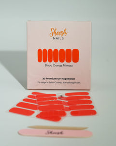 Produktfoto der Sheesh Nails UV-Nagelfolien „Blood Orange Mimosa“. Die selbstklebenden Folien in leuchtendem Orange setzen ein kräftiges Farbstatement und sorgen für einen sommerlich-frischen Look in Salonqualität. Im Vordergrund liegen die geöffneten Folien und eine Sheesh-Nagelfeile – ideal für auffällige, energiegeladene Maniküren mit Glanzfinish.