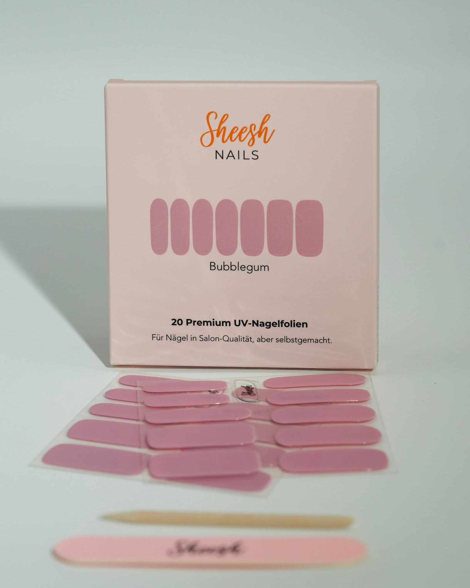 Produktfoto der Sheesh Nails UV-Nagelfolien „Bubblegum“. Die selbstklebenden Folien in sanftem Rosa sorgen für einen verspielten, femininen Look in Salonqualität. Im Vordergrund liegen die geöffneten Folien und eine Sheesh-Nagelfeile – ideal für zarte, glänzende Maniküren mit süßem Touch.