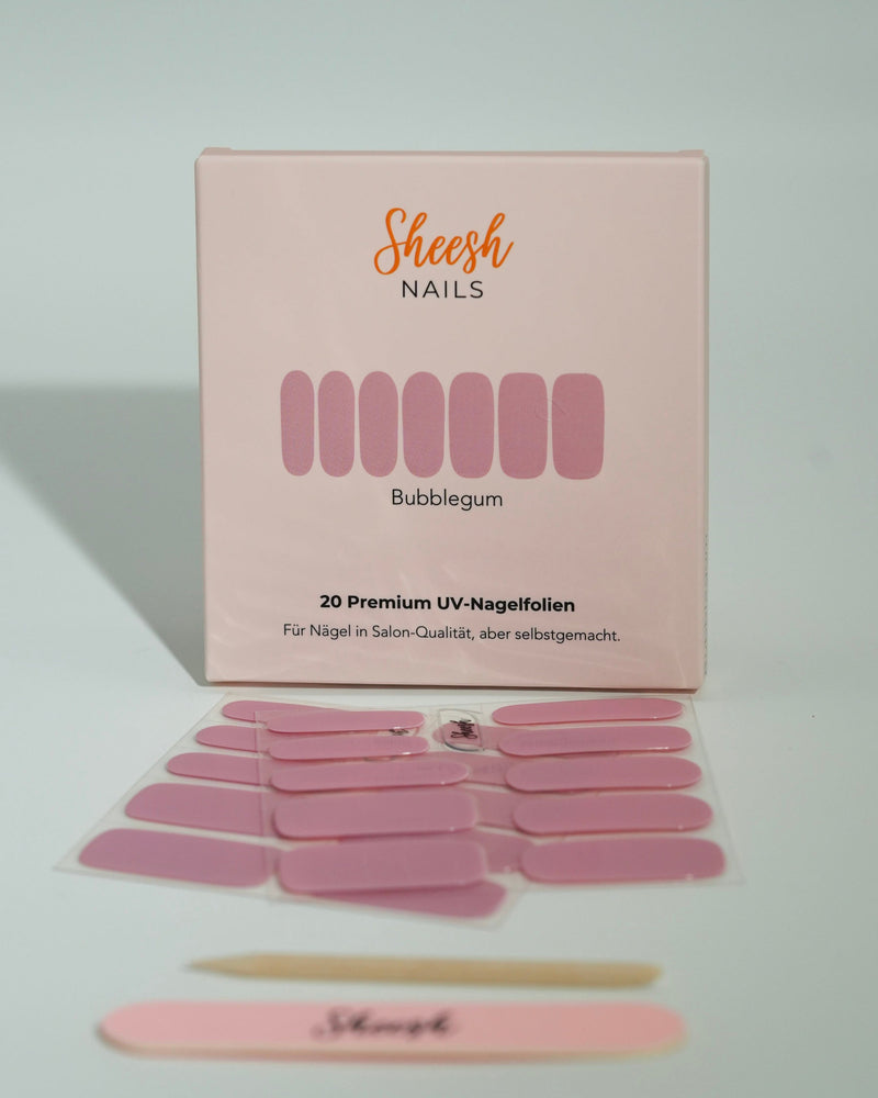 Produktfoto der Sheesh Nails UV-Nagelfolien „Bubblegum“. Die selbstklebenden Folien in sanftem Rosa sorgen für einen verspielten, femininen Look in Salonqualität. Im Vordergrund liegen die geöffneten Folien und eine Sheesh-Nagelfeile – ideal für zarte, glänzende Maniküren mit süßem Touch.