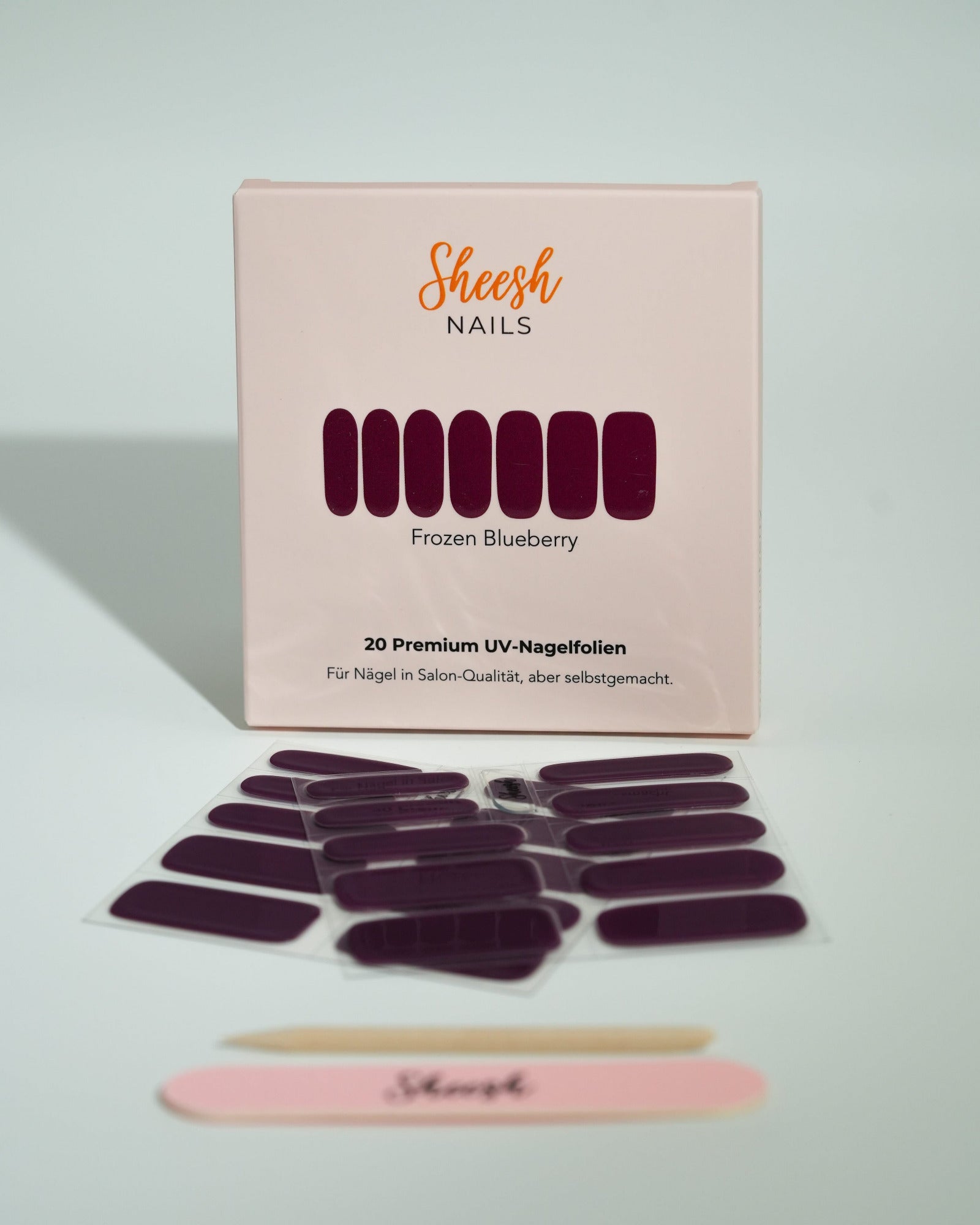 Produktfoto der Sheesh Nails UV-Nagelfolien „Frozen Blueberry“. Die selbstklebenden Folien in tiefem Lila mit kühlem Glanz verleihen den Nägeln einen edlen, modernen Look in Salonqualität. Im Vordergrund liegen die geöffneten Folien und eine Sheesh-Nagelfeile – ideal für elegante, ausdrucksstarke Maniküren mit winterlichem Charakter.