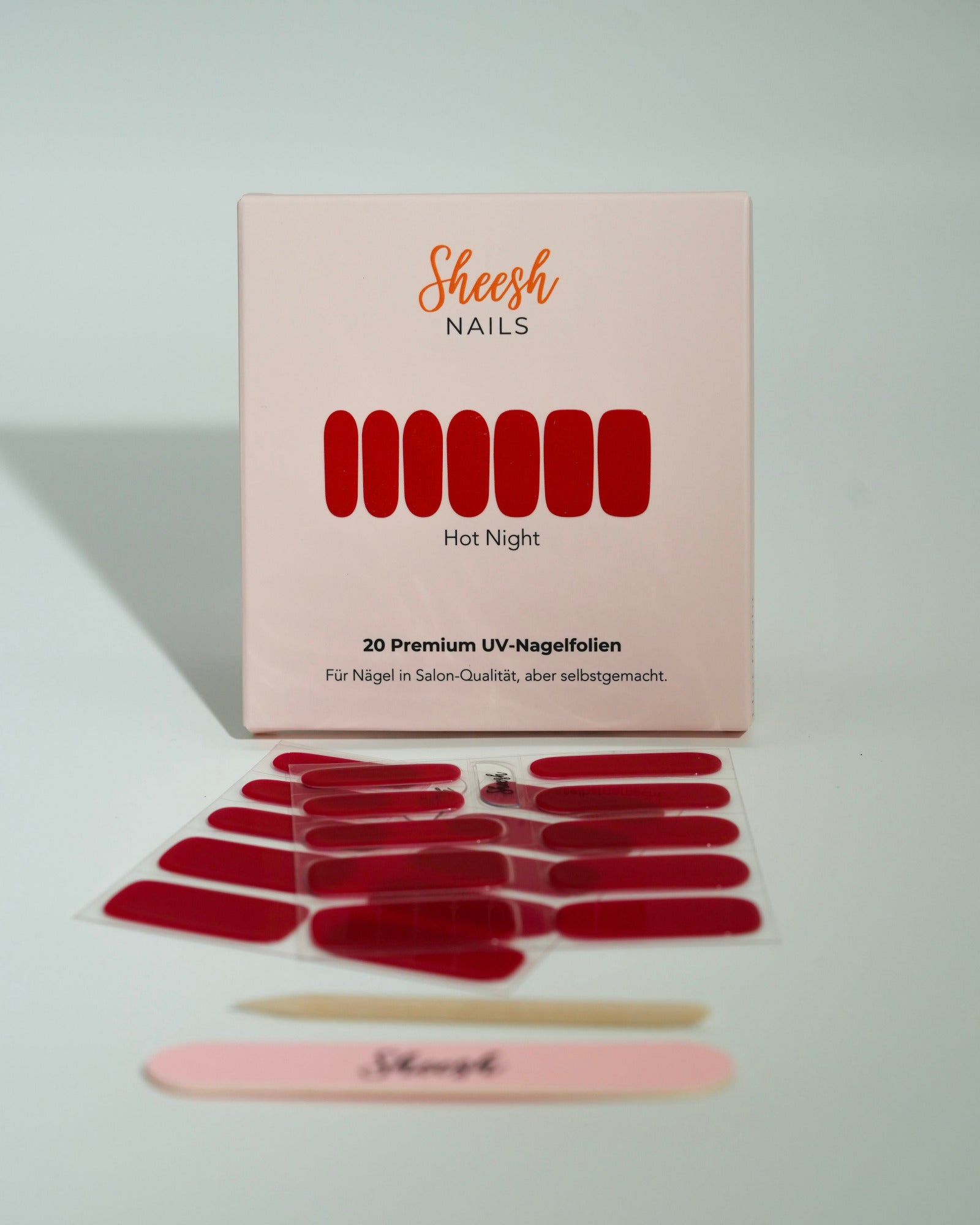 Produktfoto der Sheesh Nails UV-Nagelfolien „Hot Night“. Die selbstklebenden Folien in intensivem Rot verleihen den Nägeln einen eleganten, glänzenden Look in Salonqualität. Im Vordergrund liegen die geöffneten Folien und eine Sheesh-Nagelfeile – ideal für ausdrucksstarke, klassische Maniküren mit Glamour-Faktor.