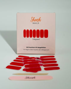Produktfoto der Sheesh Nails UV-Nagelfolien „Lifeguard“. Die selbstklebenden Folien in kräftigem Rot verleihen den Nägeln einen markanten, glänzenden Look in Salonqualität. Im Vordergrund liegen die geöffneten Folien und eine Sheesh-Nagelfeile – ideal für selbstbewusste, klassische Maniküren mit Signalwirkung.