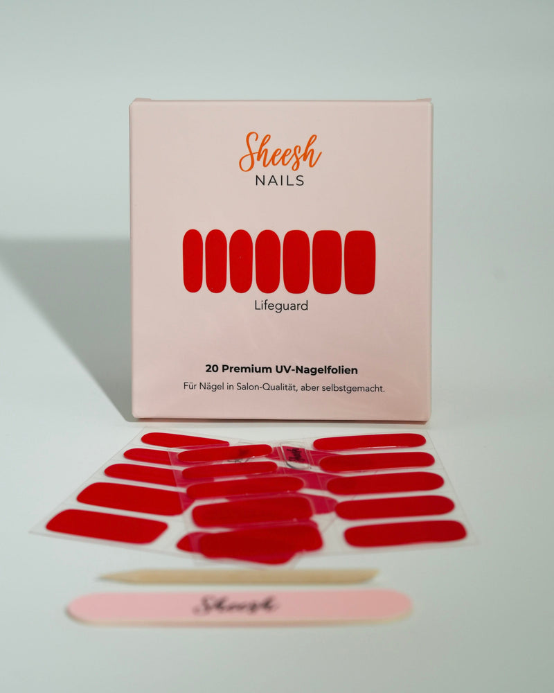 Produktfoto der Sheesh Nails UV-Nagelfolien „Lifeguard“. Die selbstklebenden Folien in kräftigem Rot verleihen den Nägeln einen markanten, glänzenden Look in Salonqualität. Im Vordergrund liegen die geöffneten Folien und eine Sheesh-Nagelfeile – ideal für selbstbewusste, klassische Maniküren mit Signalwirkung.