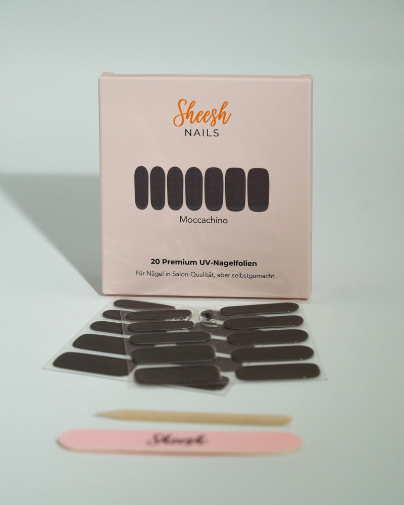 Produktfoto der Sheesh Nails UV-Nagelfolien „Mocca Chino“. Die selbstklebenden Folien in elegantem, dunklem Braun verleihen den Nägeln einen edlen, glänzenden Look in Salonqualität. Im Vordergrund liegen die geöffneten Folien und eine Sheesh-Nagelfeile – perfekt für stilvolle, zeitlose Maniküren mit Tiefenwirkung.