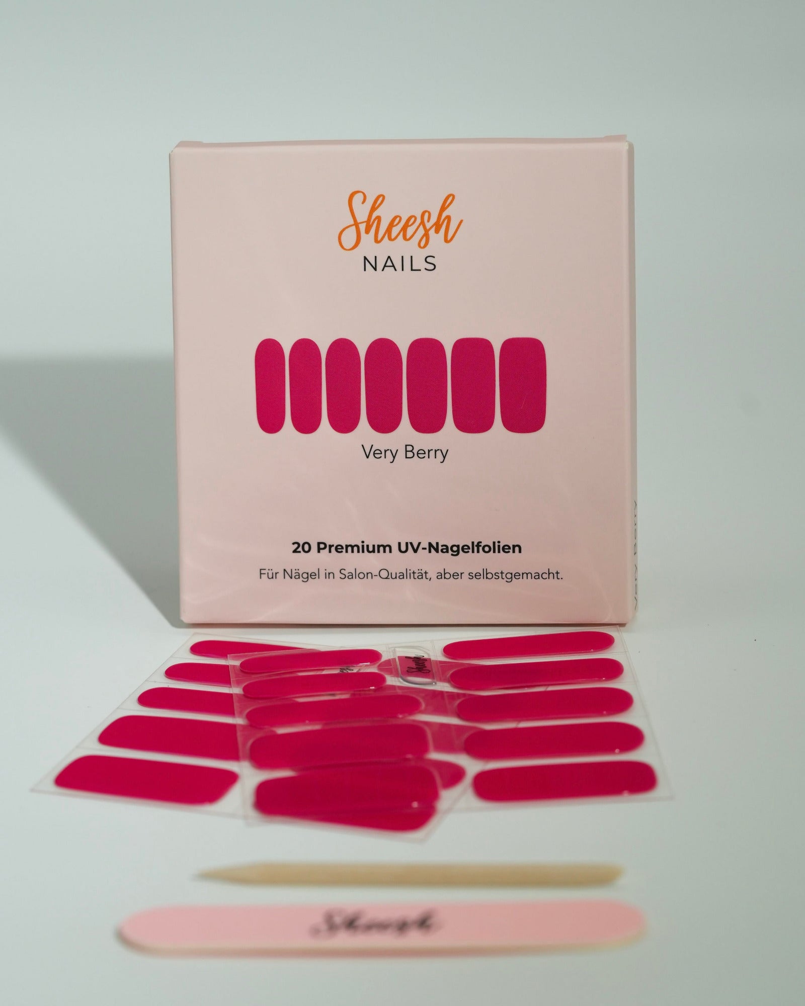 Produktfoto der Sheesh Nails UV-Nagelfolien „Very Berry“. Die selbstklebenden Folien in sattem Pink sorgen für einen auffälligen, glänzenden Look in Salonqualität. Im Vordergrund liegen die geöffneten Folien und eine Sheesh-Nagelfeile – perfekt für ausdrucksstarke, feminine Maniküren mit intensiver Farbtiefe.