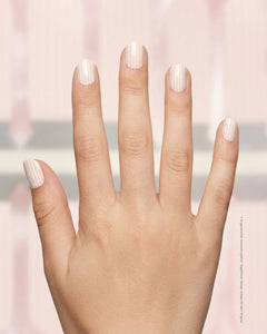 SHEESH Nails – Stripe, Bild 01: Kinderhand mit Kinder-Nagelfolie Stripe auf kurzen Nägeln vor dezentem rosa-weißem Hintergrund.