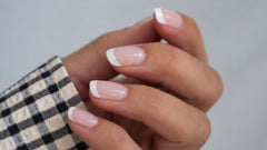 SHEESH Nails – Timeless UV-Nagelfolien, Bild 05: French-Nägel an einer Hand mit schwarz-weiß kariertem Ärmel.