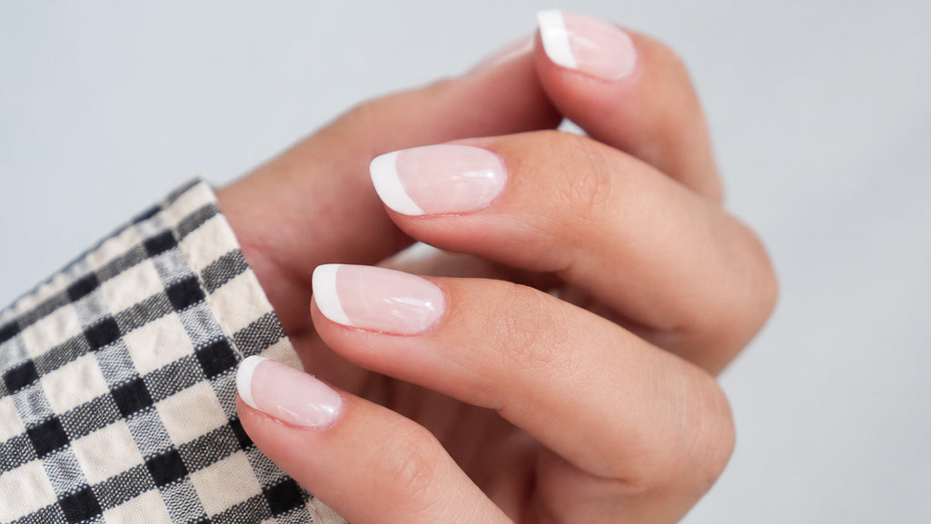 „Hand mit SHEESH Timeless UV-Nagelfolien im milchigen French-Look und weißer Spitze“